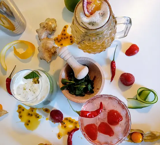 Trois cocktails sans alcool colorés entourés d’ingrédients frais et naturels, photo vue de haut