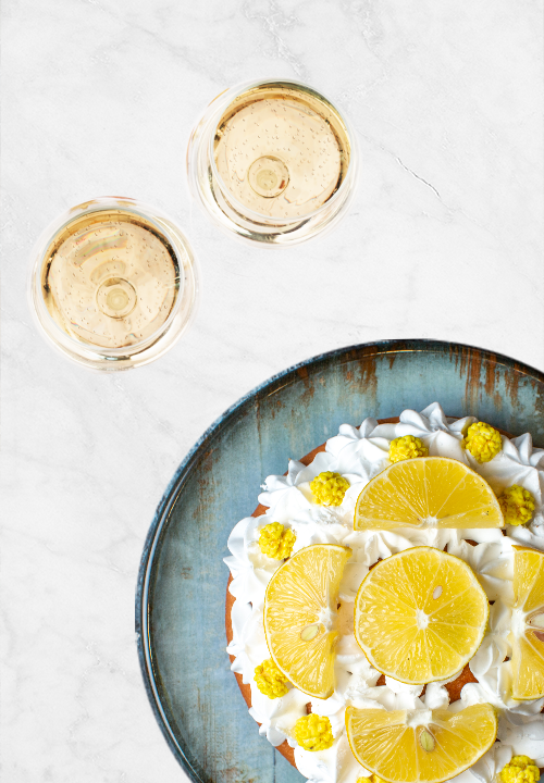 Tarte au citron vue de haut accompagnée de deux verres de boisson sans alcool pour un accord gourmand.